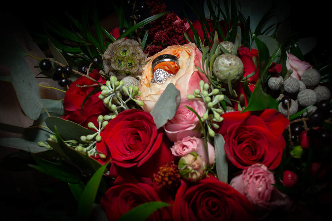 Picture of wedding rings in flowers by Sampson. Links to Wedding Photography Page.